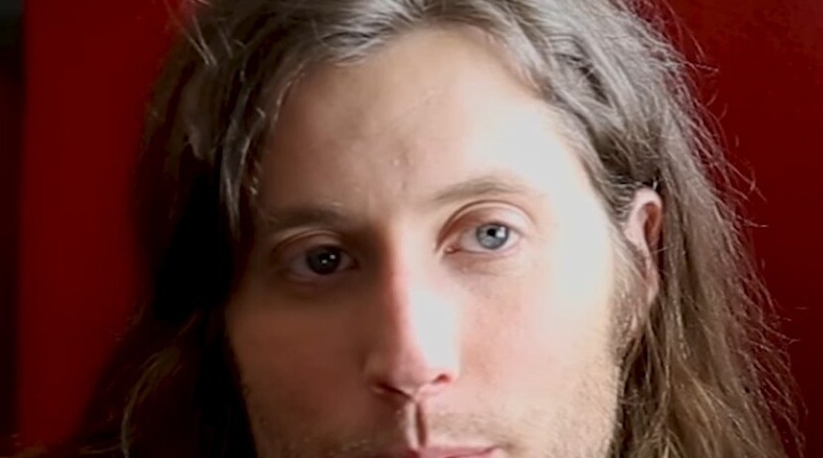 Composer Ludwig Göransson, long-haired, looking into the camera against a deep red backdrop